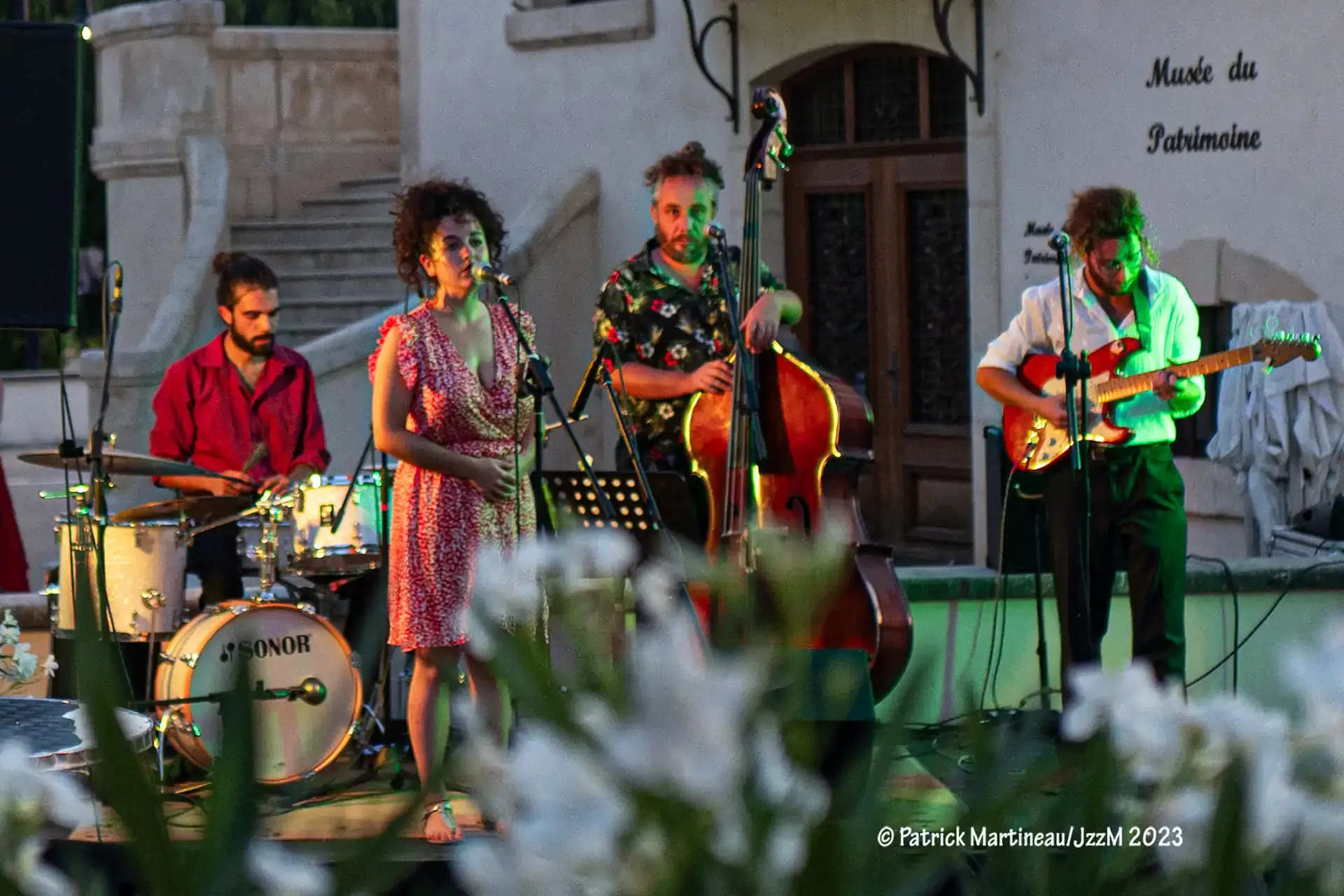 Back of a man at a concert. Hes wearing a beanie hat and a baggy denim jacket with studs. Photo with a purple hue